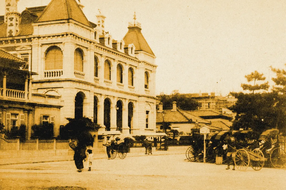 Illustration: Bund in front of the H.S. Bank, Kobe, from a period photograph (1901), redrawn as a ochre blue pencil duotone.